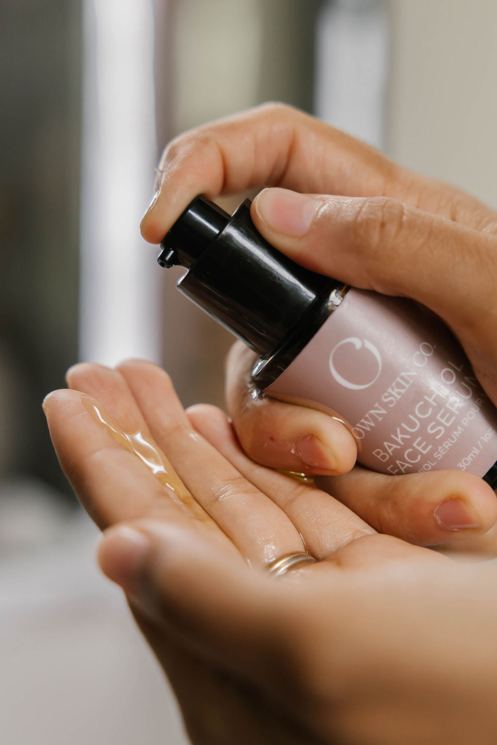 A woman dispenses OWN SKIN's Bakuchiol anti-aging-face serum onto her hand to apply to her face as a natural wrinkle defence. 