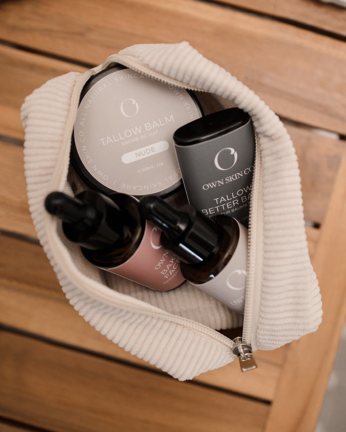 Cream makeup bag with own skin co tallow skincare items inside, serum bottles and a tallow balm