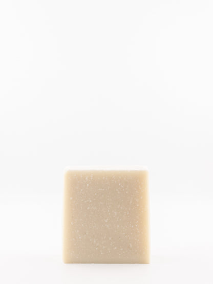 A single square bar of beef tallow eucalyptus soap with a light beige colour and fine white speckles, centred against a solid white background.