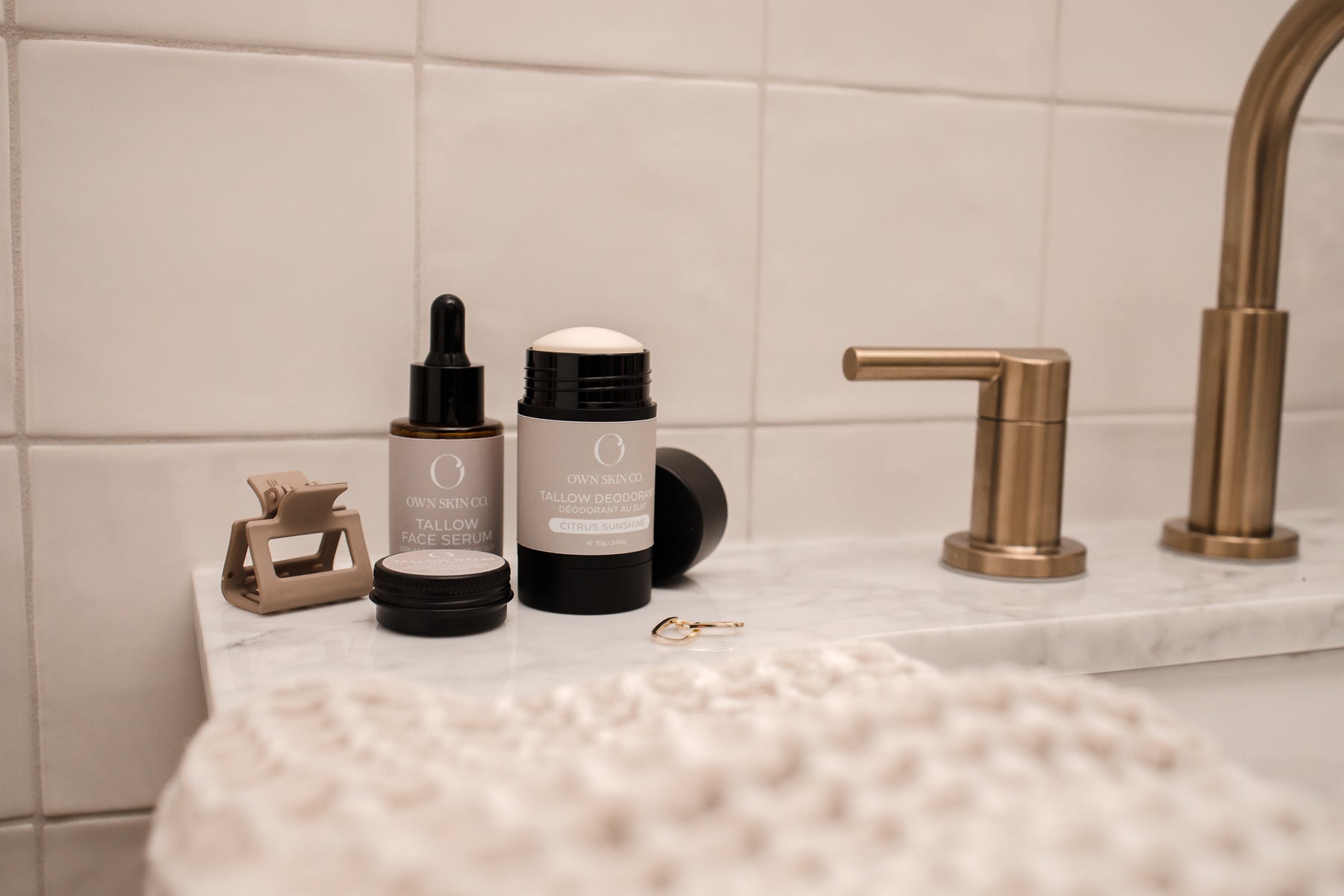 Natural beef tallow for skin and beef tallow deodorant on bathroom sink with hair clip and gold earings