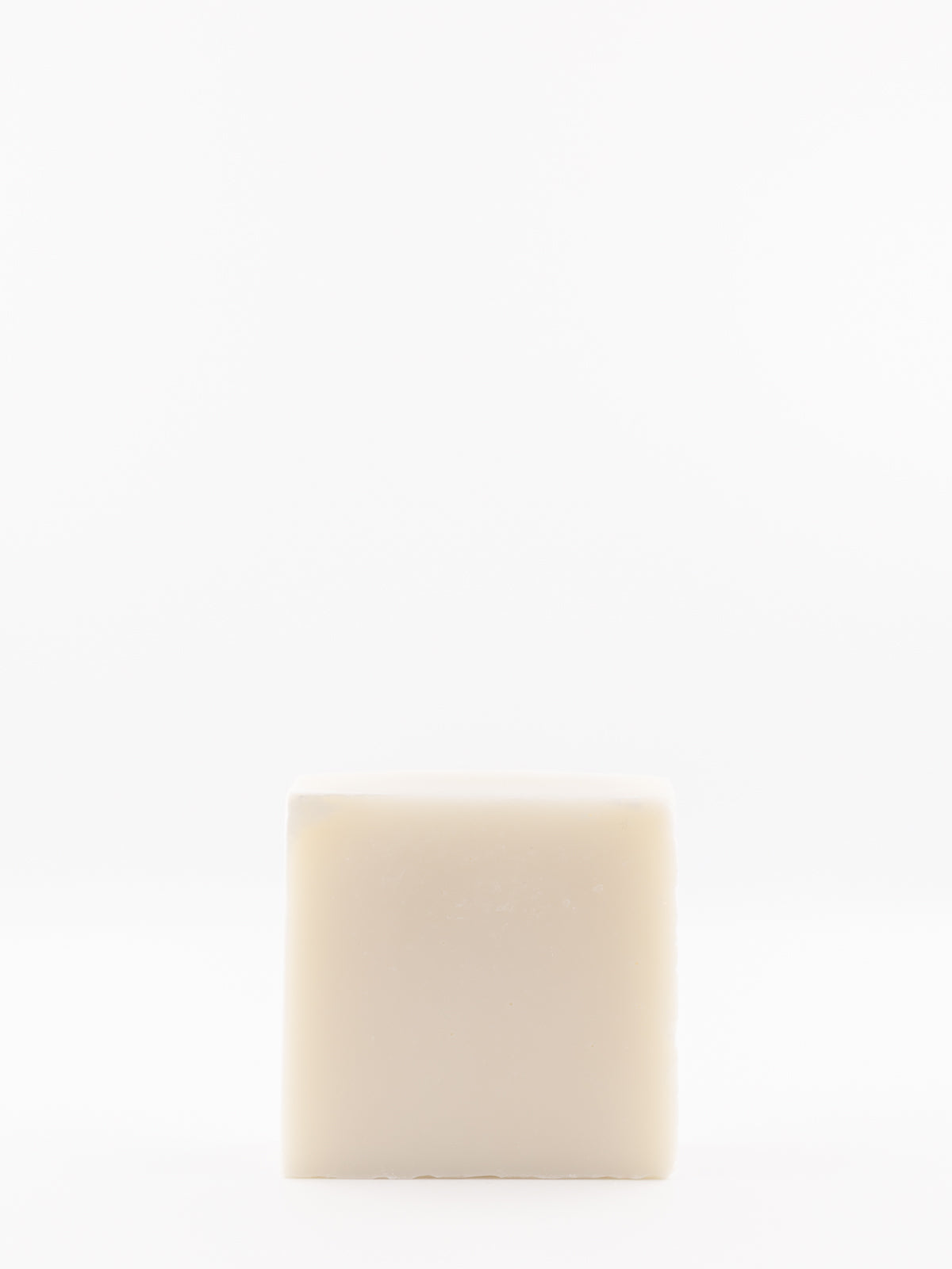 A single square bar of own skin co.'s beef tallow baby wash standing upright against a seamless white background.