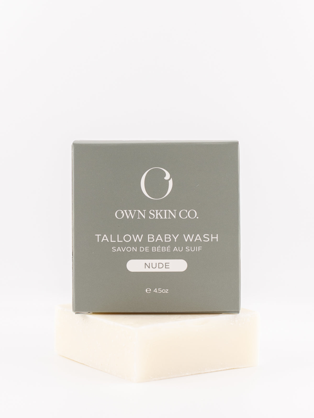 Own Skin Co. Tallow Baby Wash in the Nude scent, shown with its gray packaging box resting on a bar of creamy off-white baby wash soap against a clean white background.