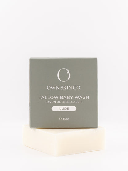 Own Skin Co. Tallow Baby Wash in the Nude scent, shown with its gray packaging box resting on a bar of creamy off-white baby wash soap against a clean white background.