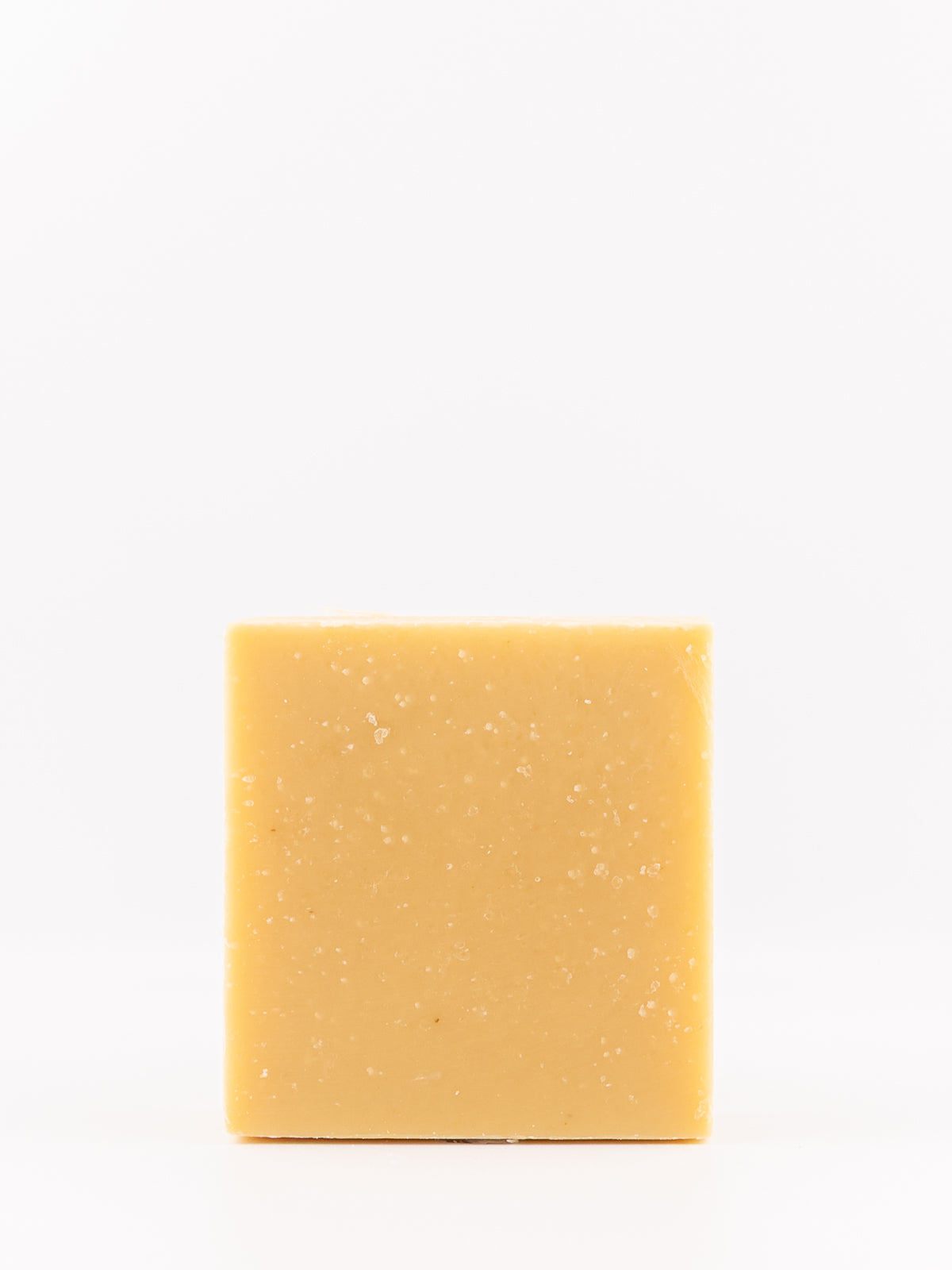 A rectangular bar of bright yellow citrus artisan soap with fine white specks, centered on a plain white background.