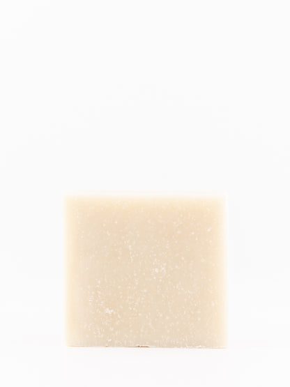 A single rectangular bar of tallow soap with a light beige, creamy texture and fine white speckles, centered against a solid white background.