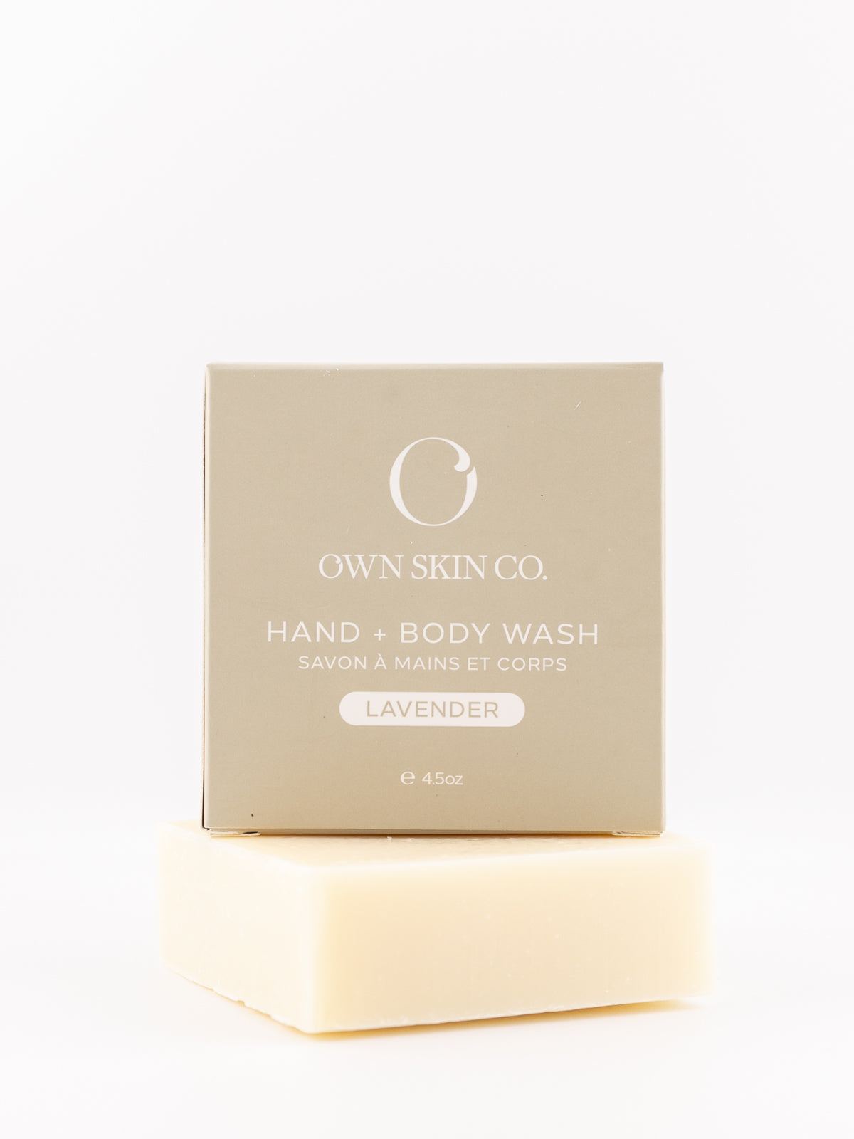 Own Skin Co. Hand & Body Wash lavender scent, shown with its beige packaging box stacked on top of a pale cream-colored soap bar against a clean white background.