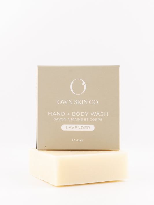 Own Skin Co. Hand & Body Wash lavender scent, shown with its beige packaging box stacked on top of a pale cream-colored soap bar against a clean white background.