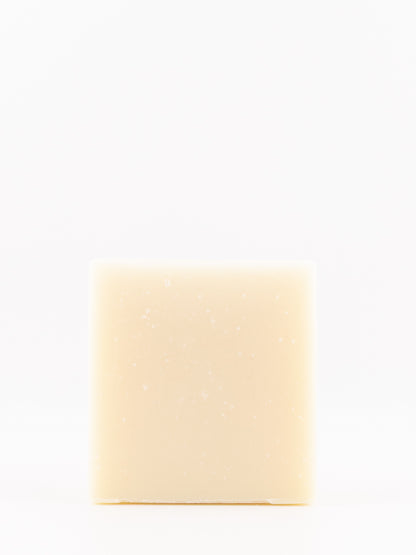 A single rectangular bar of pale cream-colored lavender soap with tiny white specks, centered on a seamless white background.