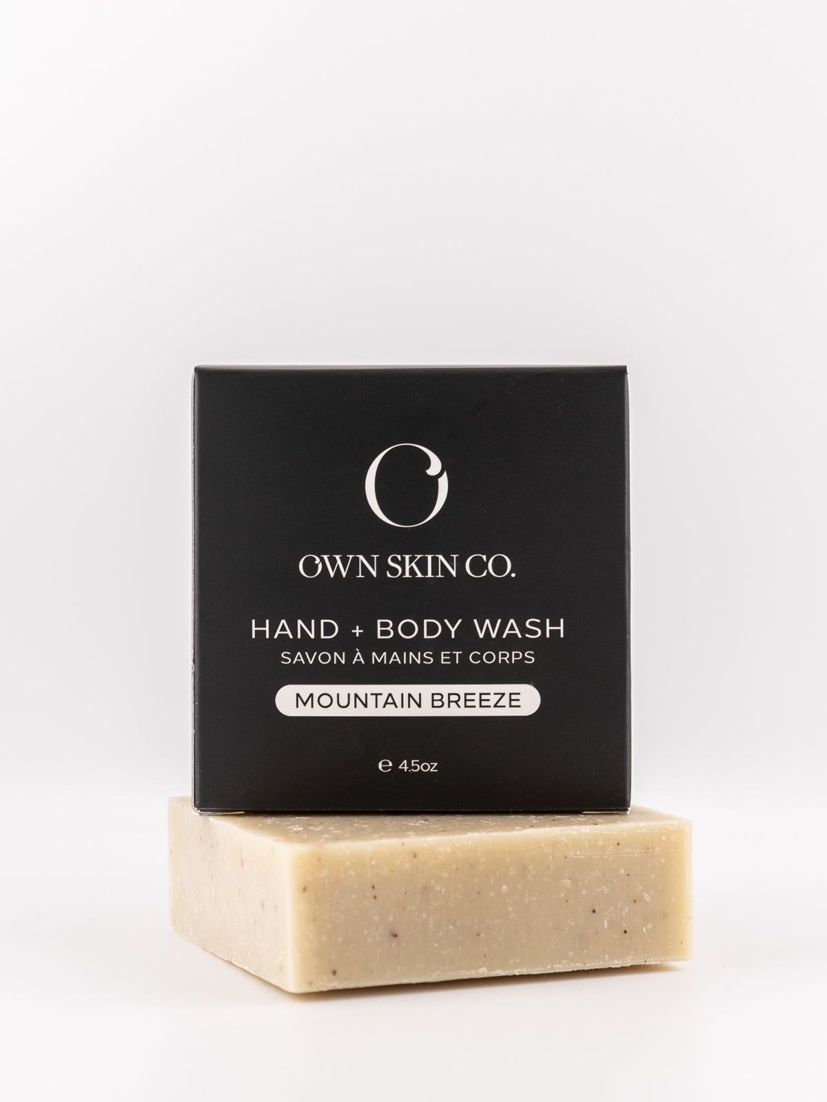 A bar of Own Skin Co. Mountain Breeze hand and body wash soap resting on its black packaging box against a clean white background.