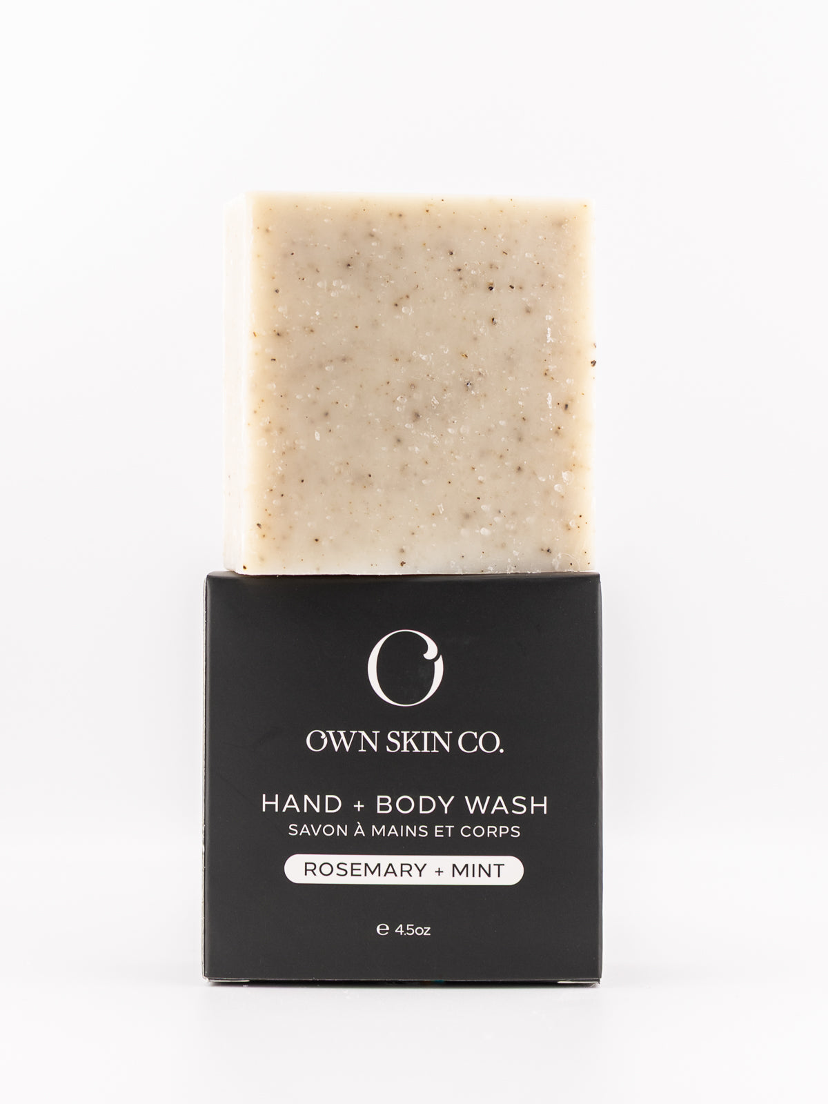 A bar of Own Skin Co. Hand & Body Wash with rosemary and mint, showing the beige speckled soap bar above its black cardboard packaging on a white background.